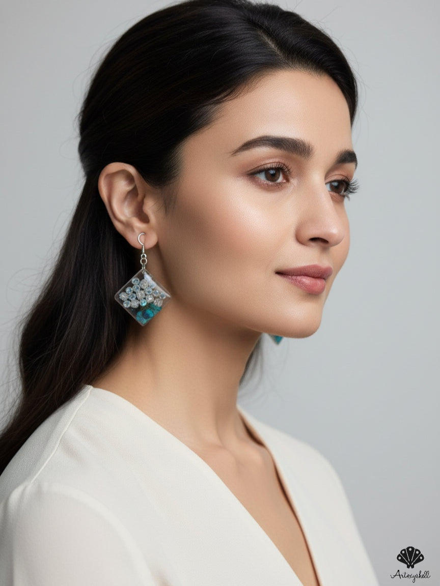 Square resin dangle earrings featuring crystal beads and preserved teal flowers