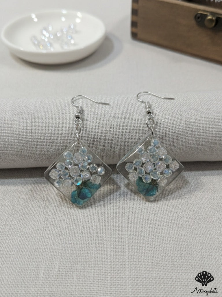 Square resin dangle earrings featuring crystal beads and preserved teal flowers